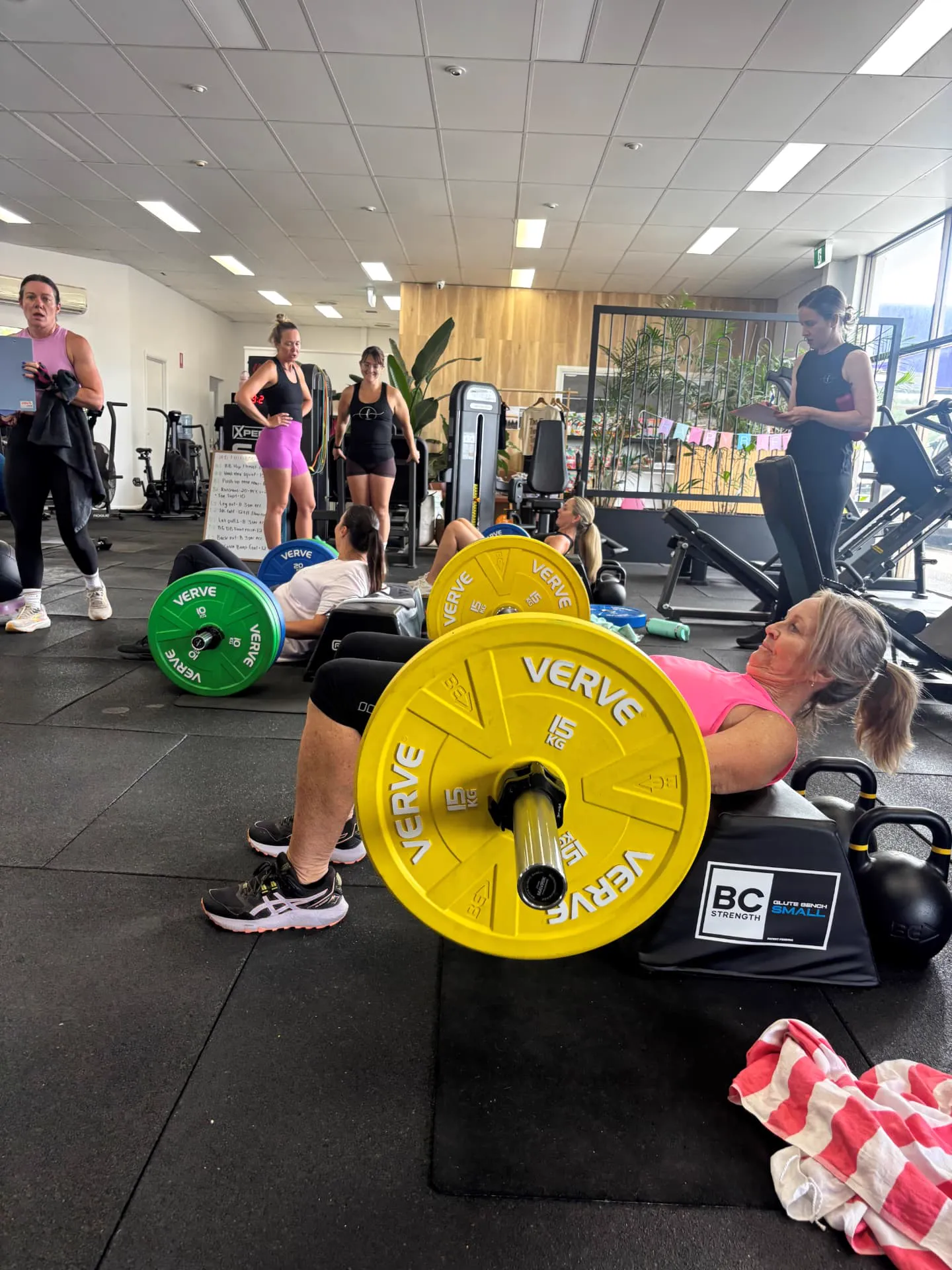 Members working through hip thrusts together on the gym floor